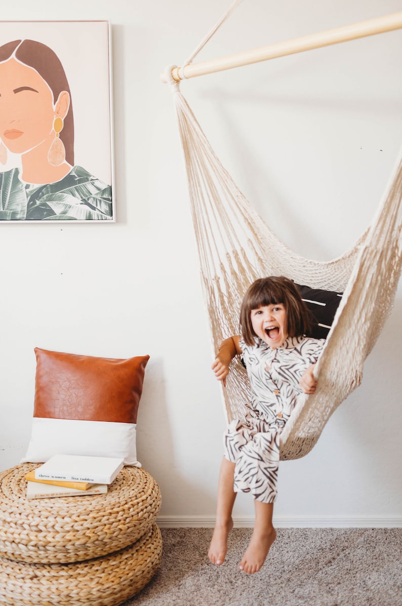 little girl sitting on a hammock chair in a bedroom