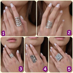 May include: Five different silver rings with unique designs. The rings are shown on a model's fingers.