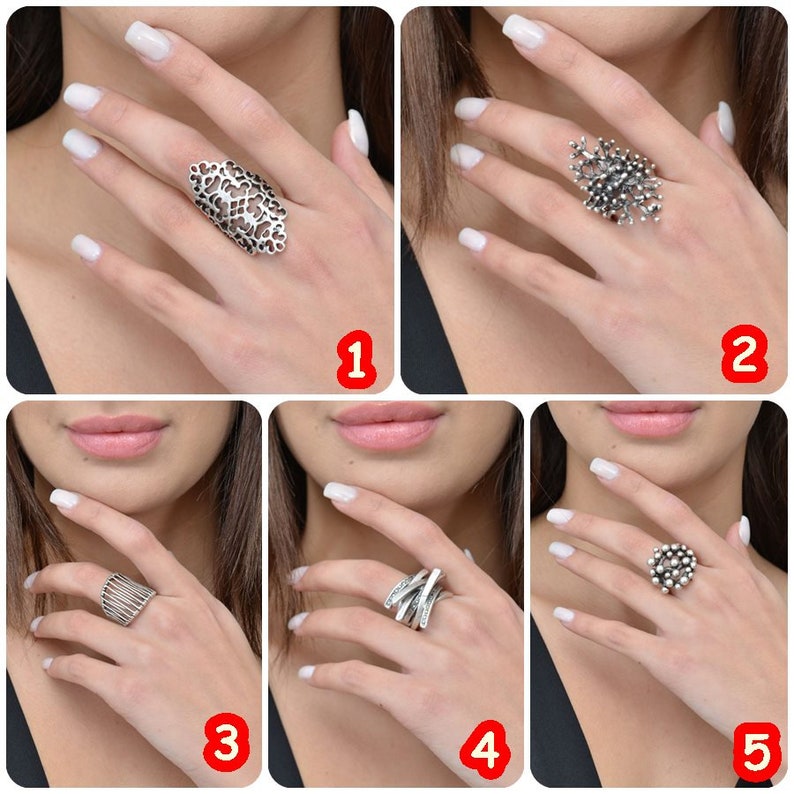 May include: Five different silver rings with unique designs. The rings are shown on a model's hand with white nail polish.