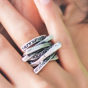 May include: A silver ring with a unique, multi-layered design. The ring is made of several thin bands that are intertwined and decorated with small beads.