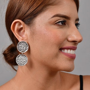 May include: Silver tone double circle drop earrings with a textured surface.