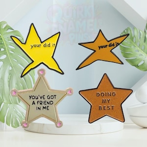 May include: Four star-shaped enamel pins with motivational phrases. The pins are in yellow, gold, and bronze colors. The phrases include "your did it", "You've got a friend in me", and "Doing my best".
