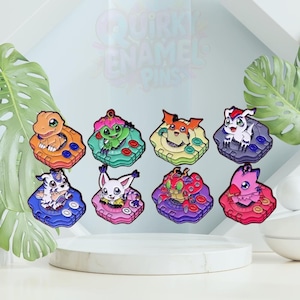 May include: Eight colourful enamel pins showcasing cartoon characters. Each pin has a unique design with vibrant colours and intricate details. The pins are displayed on a white surface with a tropical leaf background.