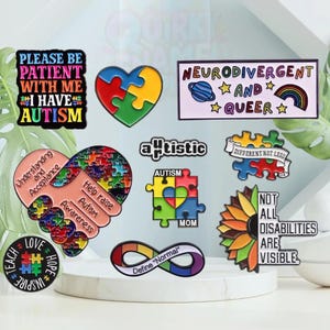 Könnte beinhalten: Eine Sammlung farbenfroher Emaille-Anstecknadeln mit Botschaften zum Thema Autismus-Bewusstsein und Neurodiversität. Die Anstecknadeln zeigen Puzzleteile, Herzen, Regenbogen und Texte wie "Please Be Patient With Me, I Have Autism" und "Neurodivergent and Queer".