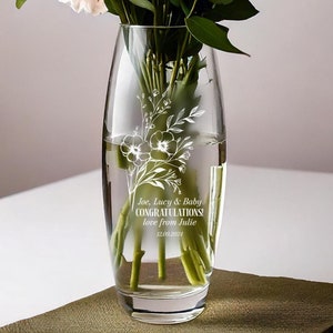 Può includere: Un vaso di vetro trasparente con un motivo floreale inciso sul lato. Il vaso è pieno d'acqua e fiori rosa. Il vaso ha un messaggio personalizzato che dice "Joe, Lucy & Baby CONGRATULATIONS! love from Julie 12.09.2024".