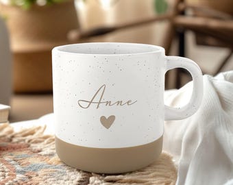 May include: White ceramic mug with a speckled finish and a brown base. The mug has the name "Anne" written in cursive with a small heart below it.