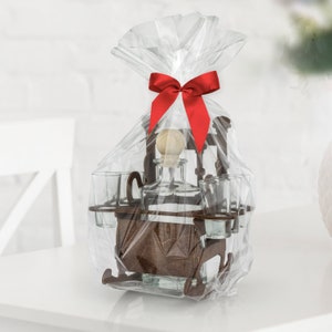May include: A wooden liquor set with a bottle and four shot glasses, wrapped in clear plastic with a red bow. The set is shaped like a rocking chair.