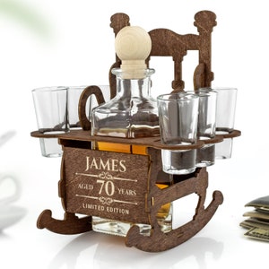 May include: Wooden rocking chair liquor dispenser with four shot glasses and a personalized label that reads "JAMES AGED 70 YEARS LIMITED EDITION".