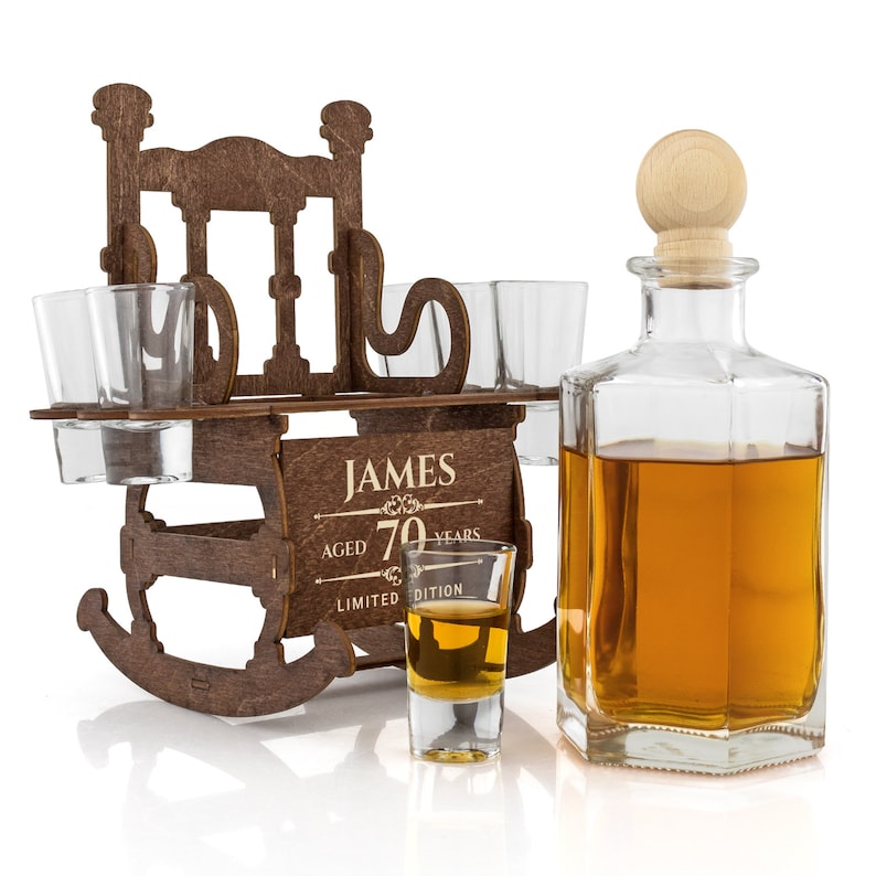 May include: Wooden rocking chair liquor dispenser with four shot glasses and a bottle of amber liquid. The dispenser is engraved with the text "JAMES AGED 70 YEARS LIMITED EDITION".