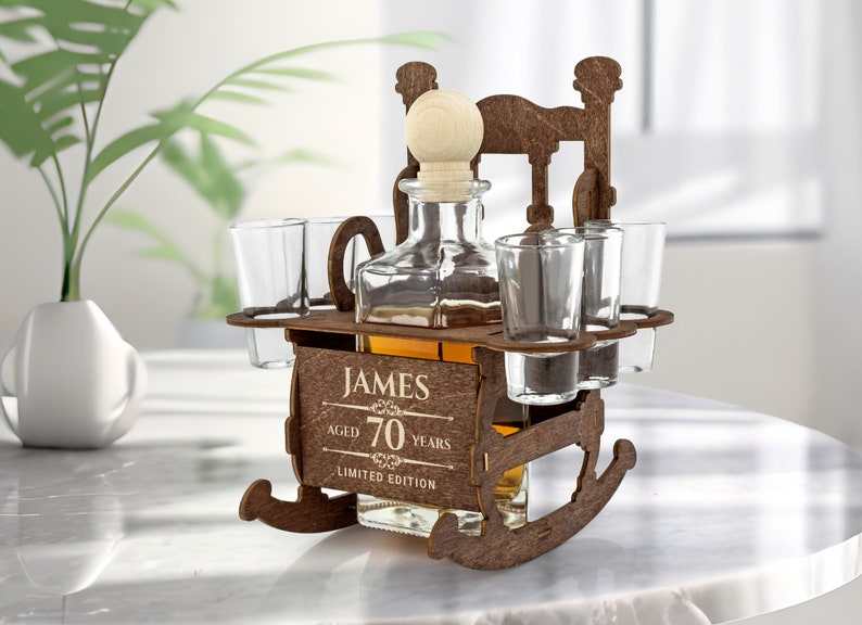 May include: Wooden rocking chair liquor dispenser with four shot glasses and a bottle of liquor. The dispenser is engraved with the text "James Aged 70 Years Limited Edition".