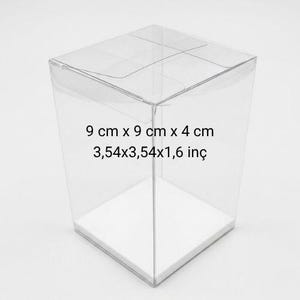 May include: A clear, transparent plastic box with a white base. The box is 9 cm x 9 cm x 4 cm and 3.54 x 3.54 x 1.6 inches. The box is designed to hold small items.