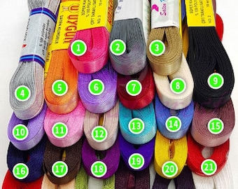 May include: Twenty-seven spools of ribbon in various colors, including red, orange, yellow, green, blue, purple, pink, brown, black, and white. The spools are arranged in three rows, with the numbers 1 through 27 printed on the spools.