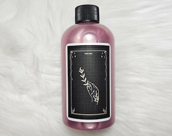 Könnte beinhalten: Eine rosa Flasche mit einem schwarzen Etikett, auf dem "The Fool" steht, und einer schwarz-weißen Illustration einer Hand, die nach einem Zweig greift.