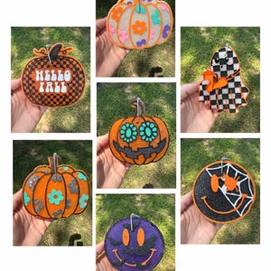 May include: A collage of Halloween-themed pumpkin and ghost-shaped ornaments. The ornaments feature various designs, including floral patterns, checkerboard patterns, and smiling faces. Some have glitter accents and the text "Hello Fall".