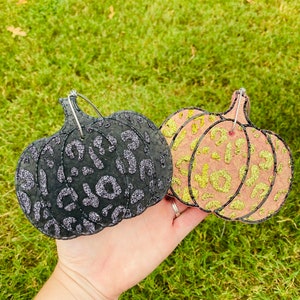 Pu&ograve; includere: Due decorazioni a forma di zucca. Una &egrave; nera con stampa leopardata glitterata argento, l'altra &egrave; pesca con stampa leopardata glitterata oro. Entrambe hanno un anello di filo per appenderle.