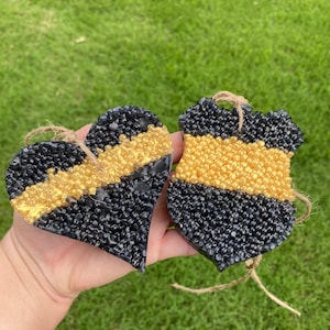 May include: Two black and gold car air fresheners, one shaped like a heart and the other shaped like a police badge. Both have a thin gold stripe across the middle.