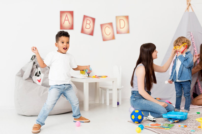 May include: A playroom with a grey beanbag chair, a white table and chair, and a teepee tent. Three children are playing with toys. The wall has colourful letters A, B, C, and D.