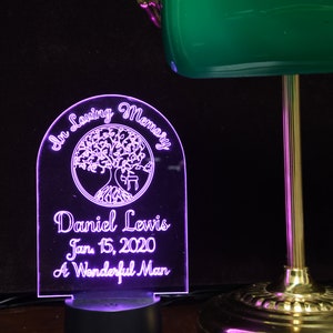 May include: A glowing memorial plaque with the words "In Loving Memory" above a tree design. Below the tree, the name "Daniel Lewis" and the date "Jan. 15, 2020" are inscribed, along with the phrase "A Wonderful Man."