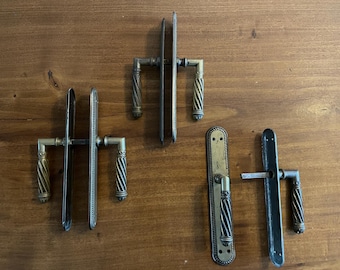 May include: Four antique door handles with ornate details. Two are silver with a decorative border, one is black, and one is silver with a simple design.