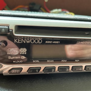 May include: A silver Kenwood KDC-4021 car stereo with a CD player and radio controls. Features include a digital display, buttons for functions like scan, random, and repeat, and a CD MD-Changer Control.