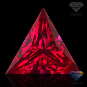 Puede incluir: Una gema triangular facetada de color rojo intenso. Los ángulos agudos y los reflejos internos crean una exhibición deslumbrante sobre un fondo negro. La imagen muestra el brillo y la claridad de la gema.
