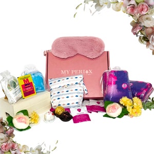 May include: A pink box with the text "MY PERIODX" on the front, containing a variety of items, including a pink eye mask, a white and blue patterned pouch, a clear bag with a blue and white patterned item, a yellow and pink patterned item, and a small wooden box with a white and blue patterned item. The box is surrounded by flowers.