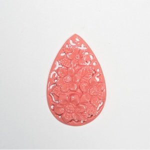 Puede incluir: Un colgante en forma de lágrima de color rosa coral con un diseño floral. El colgante está hecho de resina y tiene un diseño delicado e intrincado.