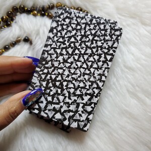May include: A deck of playing cards with a black and white geometric pattern on the back. The pattern is made up of small triangles.
