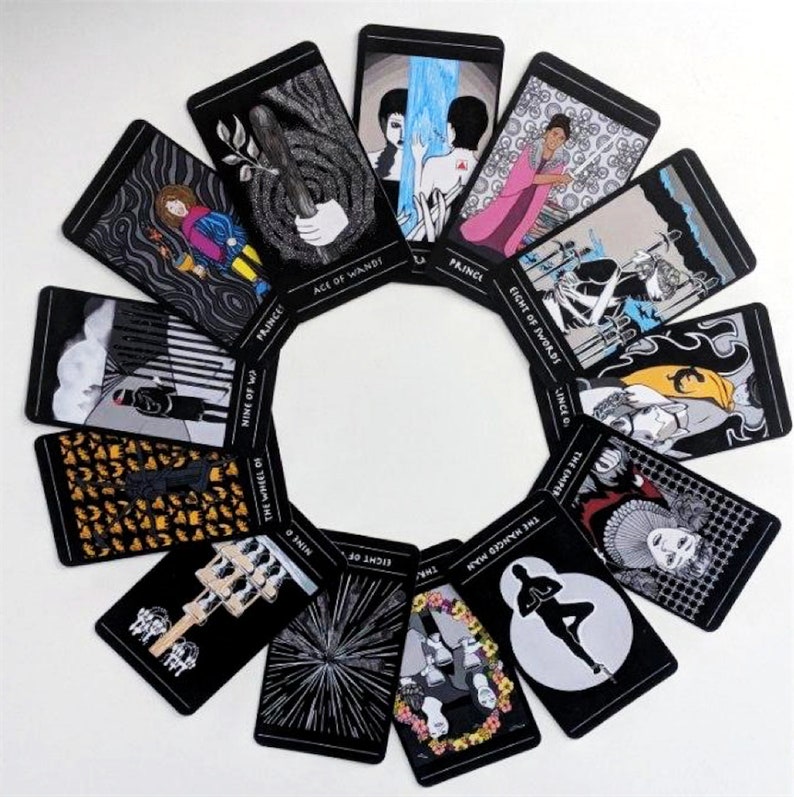 May include: A set of tarot cards with black backgrounds and colorful illustrations. The cards are arranged in a circle, with the names of the cards visible. The cards include the Ace of Wands, Prince, Eight of Swords, Nine of Wands, The Hanged Man, The Wheel of Fortune, Eight of Pentacles, and Nine of Cups.