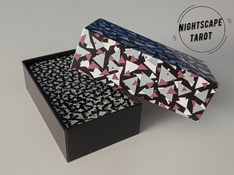 May include: A black box with a geometric pattern on the lid. The box is open and the inside is lined with a black and white geometric pattern. The box is labeled "Nightscape Tarot".