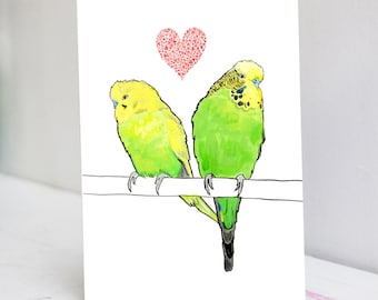 Pode incluir: Uma ilustração em aquarela de dois periquitos verdes e amarelos empoleirados em um galho. Um coração rosa com corações menores dentro está acima dos pássaros.