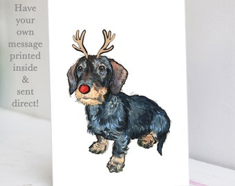 May include: A Christmas card featuring a black and brown dachshund wearing a red nose and reindeer antlers. The card has the text "Have your own message printed inside & sent direct!"