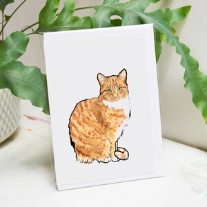 May include: A greeting card featuring a watercolor illustration of an orange tabby cat with white markings. The cat is sitting with its front paws tucked under its body and looking directly at the viewer.