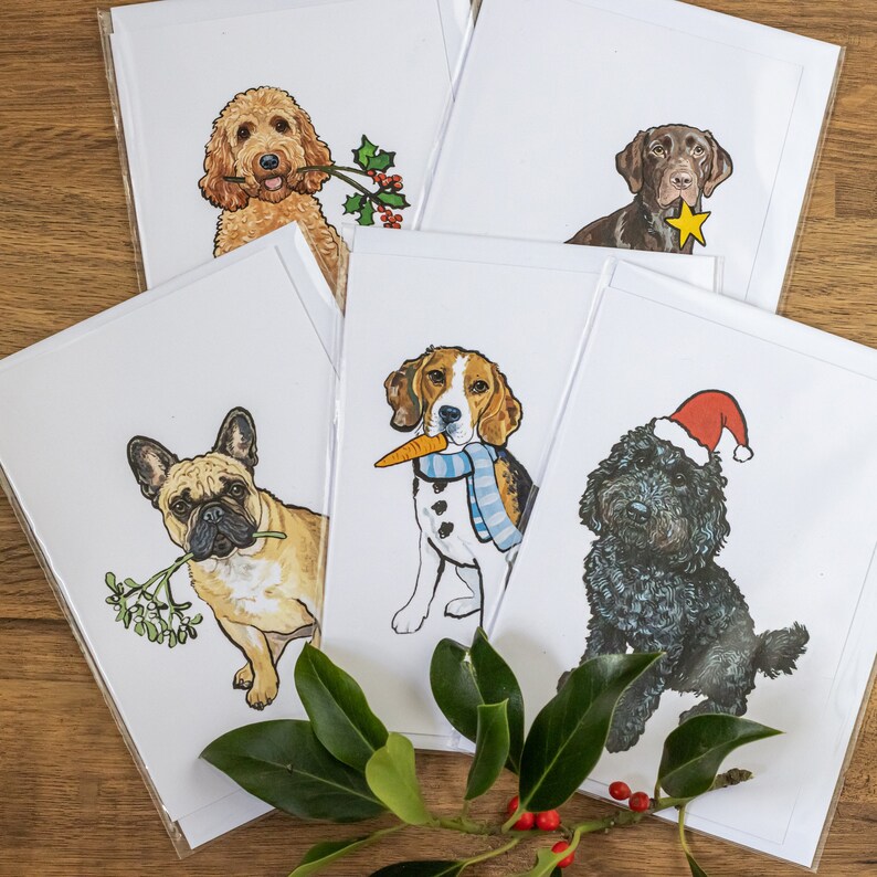Peut inclure: Ensemble de quatre cartes de No&euml;l repr&eacute;sentant diff&eacute;rentes races de chiens. Chaque carte repr&eacute;sente un chien portant un accessoire festif, comme un chapeau de P&egrave;re No&euml;l, une &eacute;charpe ou du gui.