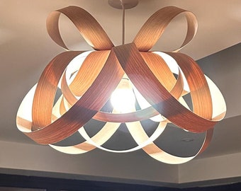 May include: A wooden ceiling light fixture with a unique, modern design. The light is made of multiple layers of wood that are interwoven to create a unique and stylish look. The light is illuminated by a single light bulb.