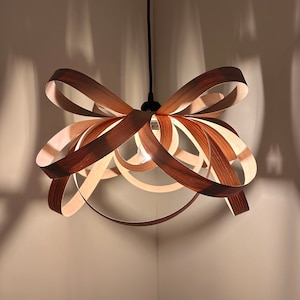 May include: A wooden pendant light fixture shaped like a bow. The light fixture is made of thin strips of wood that are woven together to create a unique and modern design.