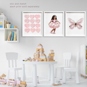 May include: Three framed art prints with white frames. The prints feature a watercolor design of pink hearts, a ballerina in a pink dress, and a pink butterfly. The text "mix and match each print sold separately" is at the top.