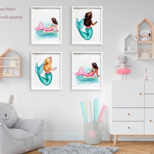 May include: Four framed watercolor prints of mermaids. Each mermaid has a different skin tone, hair color, and tail color. The mermaids are depicted in a whimsical style, with a crown on their heads. The prints are displayed on a white wall.
