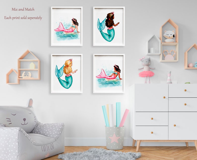 May include: Four framed watercolor prints of mermaids. Each mermaid has a different skin tone, hair color, and tail color. The mermaids are depicted in a whimsical style, with a crown on their heads. The prints are displayed on a white wall.