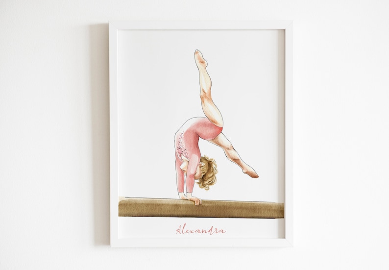 K&ouml;nnte beinhalten: Eine Aquarell-Illustration einer jungen Turnerin, die einen Handstand auf einem Schwebebalken macht. Die Turnerin tr&auml;gt einen rosafarbenen Trikot mit Blumendetails und hat blonde Haare. Die Illustration ist in einem wei&szlig;en Rahmen gerahmt und der Name "Alexandra" ist in rosa unter dem Balken geschrieben.