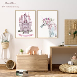 K&ouml;nnte beinhalten: Zwei Aquarelldrucke, einer von einem rosafarbenen Schloss und einer von einem Einhorn mit einer Blumenkrone. Die Drucke sind in hellem Holz gerahmt und an einer wei&szlig;en Wand aufgeh&auml;ngt. Der Text "Mix and Match" und "Each print sold separately" ist oben im Bild sichtbar.