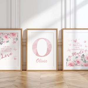 Könnte beinhalten: Drei gerahmte Kunstdrucke mit goldenen Rahmen. Die Drucke zeigen Aquarelldesigns von Rosen, Schmetterlingen und inspirierenden Zitaten. Ein Druck hat das Wort "Love", ein anderer den Buchstaben "O" und den Namen "Olivia", und der dritte sagt "Made".