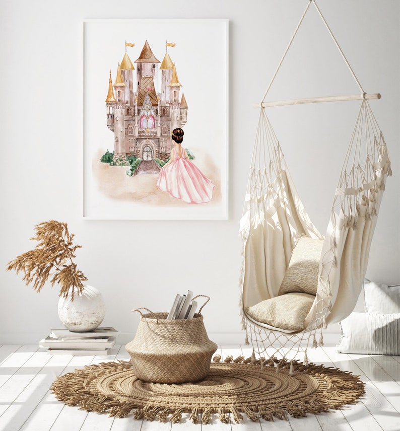 May include: A framed watercolor print featuring a large castle with golden spires and a figure in a flowing pink gown standing before it. The artwork is displayed on a white wall above a woven basket, a vase with dried grass, and a hanging chair.