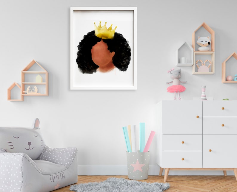 May include: A framed watercolor print featuring a profile of a person with dark skin and black curly hair, wearing a gold crown. The artwork is set against a white background, framed in a white border, and is displayed in a child's room.
