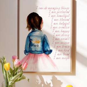 May include: A framed wall art print featuring a watercolor illustration of a child wearing a blue denim jacket with a gold crown and the name Marin, paired with a pink skirt. The text lists positive affirmations including I am enough.