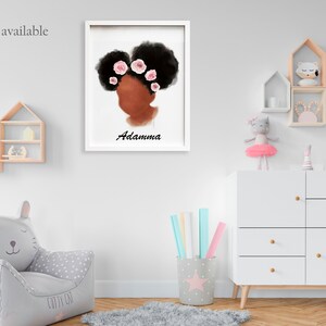 May include: A framed art print featuring a stylized illustration of a woman's profile with dark hair adorned with pink flowers. The name "Adamma" is written below the image in black script. The artwork is displayed in a child's room.