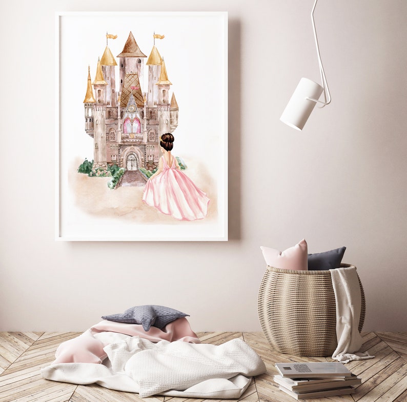 May include: A framed watercolor print featuring a large castle with golden spires and a central arched entrance. In the foreground, a figure with dark hair in an updo wears a flowing pink gown, facing toward the castle entrance.