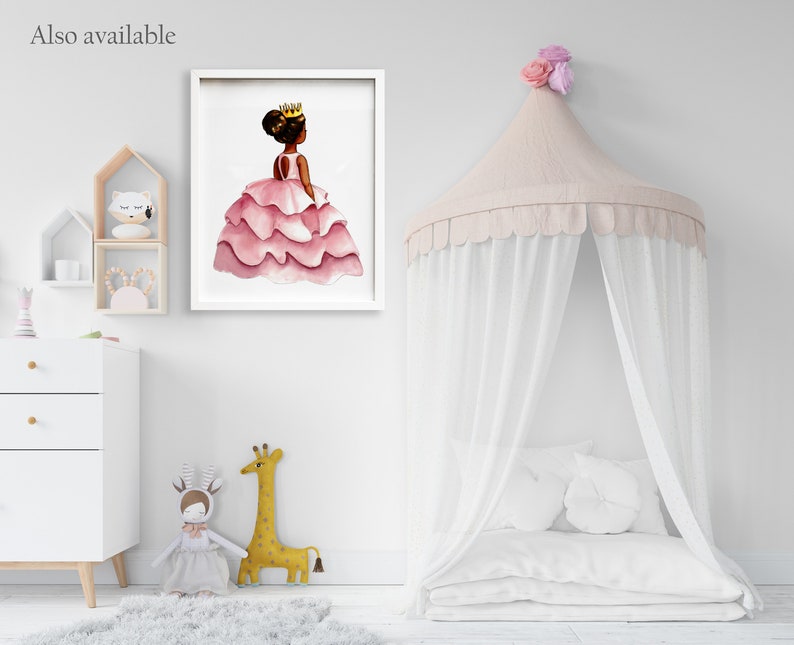 May include: A framed watercolor print of a young princess in a pink layered dress and gold crown. The image is displayed in a white frame. The text "Also available" is in the upper left corner. The room also features a canopy bed and decorative toys.