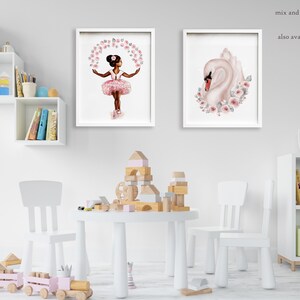 K&ouml;nnte beinhalten: Zwei gerahmte Drucke, einer mit einem jungen M&auml;dchen in einem rosa Tutu, das mit rosa Blumen tanzt, und der andere mit einem wei&szlig;en Schwan mit rosa Blumen. Die Drucke h&auml;ngen an einer wei&szlig;en Wand in einem Raum mit einem wei&szlig;en Tisch und St&uuml;hlen.