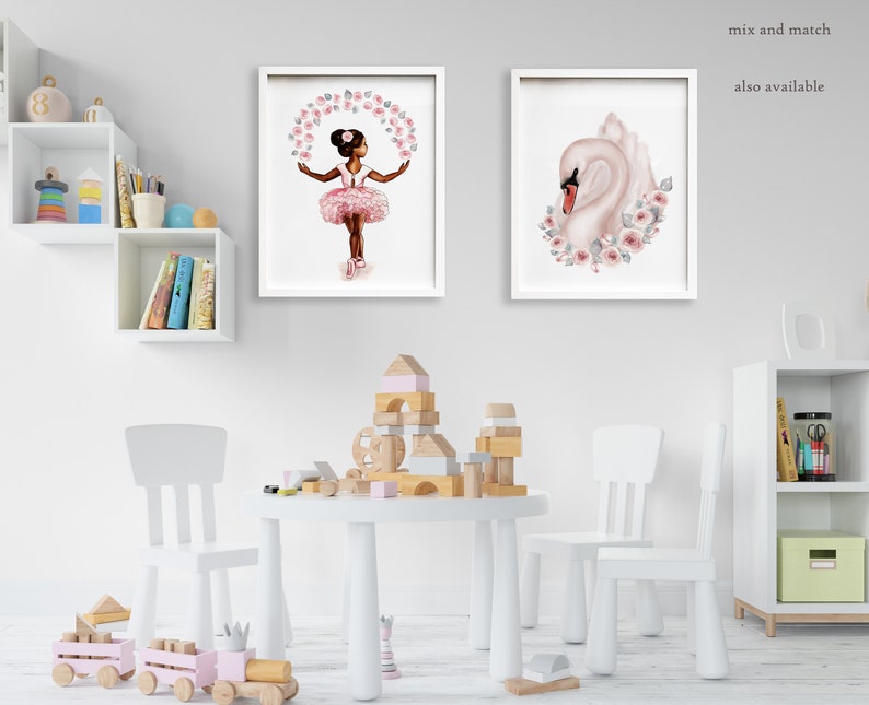 K&ouml;nnte beinhalten: Zwei gerahmte Drucke, einer mit einem jungen M&auml;dchen in einem rosa Tutu, das mit rosa Blumen tanzt, und der andere mit einem wei&szlig;en Schwan mit rosa Blumen. Die Drucke h&auml;ngen an einer wei&szlig;en Wand in einem Raum mit einem wei&szlig;en Tisch und St&uuml;hlen.